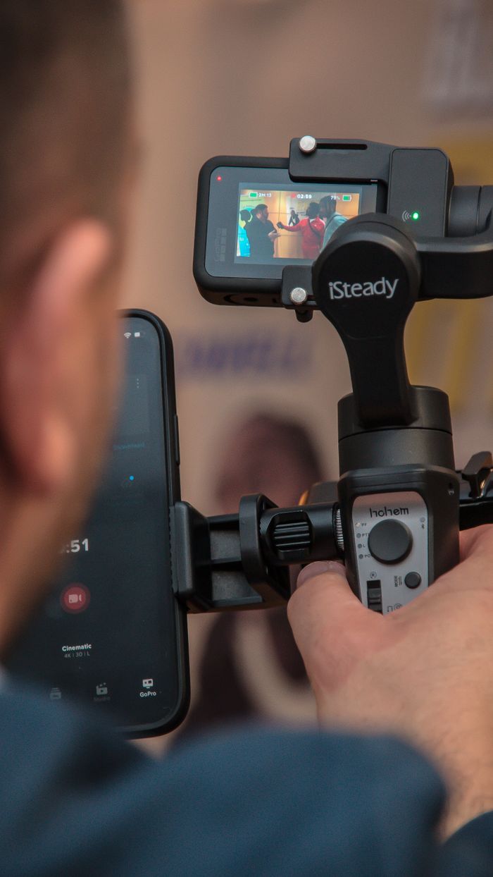 A man films with a smartphone stabilizer, using modern technology to keep the footage smooth.